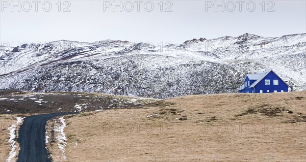 Icelandic landscape with blue chalet farm house in Reykjanes peninsula, Mountains covered in snow