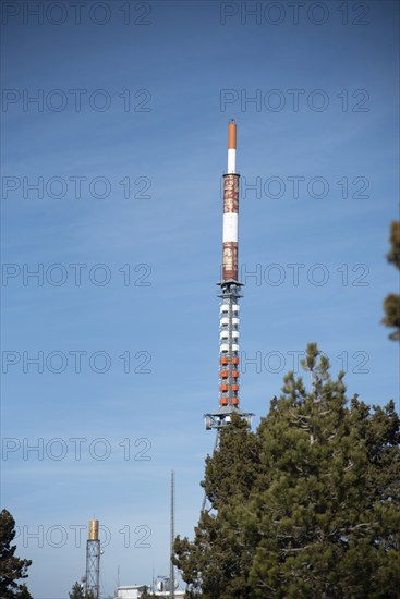 Communication tower on a building with 4G 5G antenna and satellite dish against blue sky. Mobile