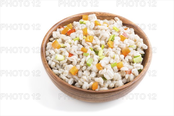 Pearl barley porridge with vegetables in wooden bowl isolated on white background. Side view, close