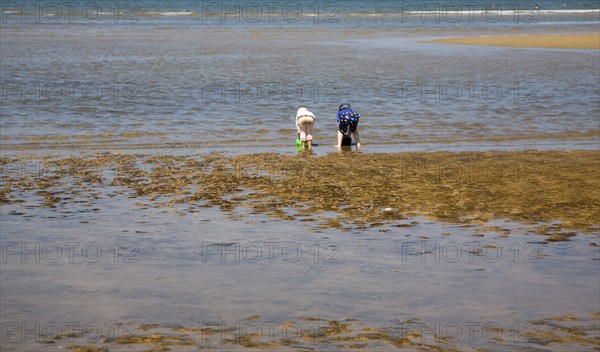 Two children playing with buckets in the sea at Hunstanton, north Norfolk coast, England, United