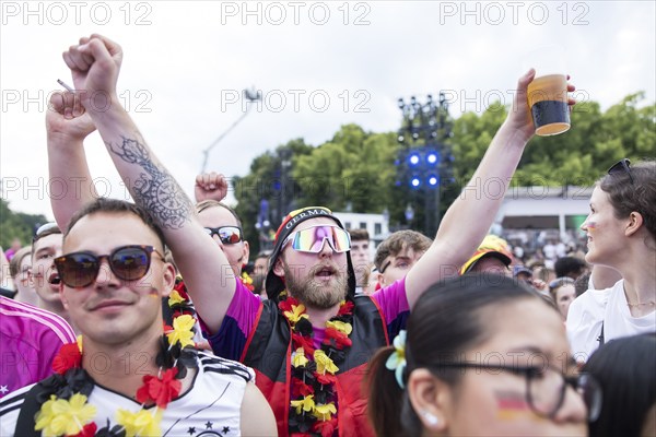 A fan celebrates with sunglasses, beer and feather boa in the fan zone at the Brandenburg Tor