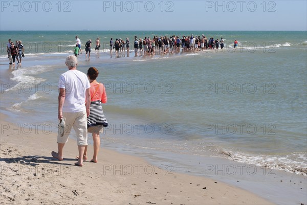 Ttourists standing at the northern tip of Denmark where the Baltic Sea and North Sea meet at Skagen