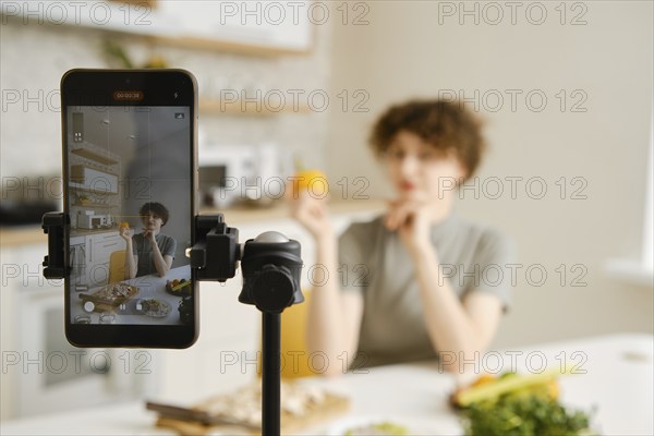 Professional nutritionist filming on her smartphone tutorial about healthy eating on her kitchen