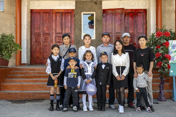 Family and school children, group posing in front of the school on the first day of school,
