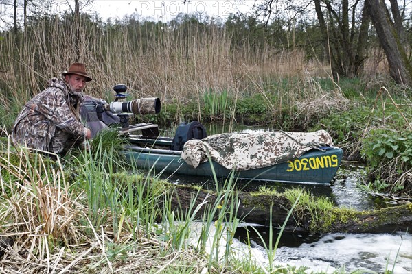 A canoe with camouflaged camera in a swamp, surrounded by vegetation and quiet nature, boat of a