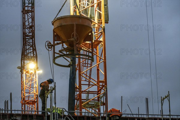 Concrete work, at dusk, on a large construction site building a residential and commercial complex,