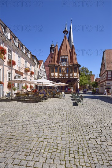 Historic town hall with outdoor area of the confectionery and café Leyhausen under a cloudless blue