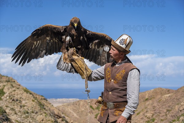 Traditional Kyrgyz eagle hunter with eagle in the mountains, near Kysyl-Suu, Kyrgyzstan, Asia