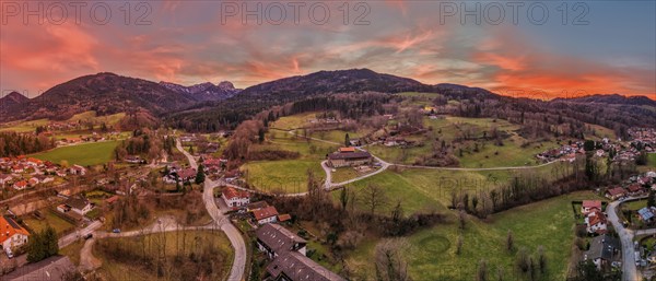Panoramic view of a village in a hilly landscape at sunset with a red-coloured sky, Bad Feilnbach