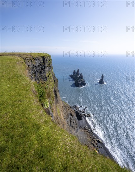 Steep coast, view from steep cliff to the rocks Reynisdrangar in the water, at Reynisfjara beach,
