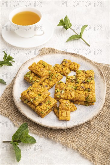 Traditional iranian dessert sohan with cup of green tea on a gray concrete background and linen