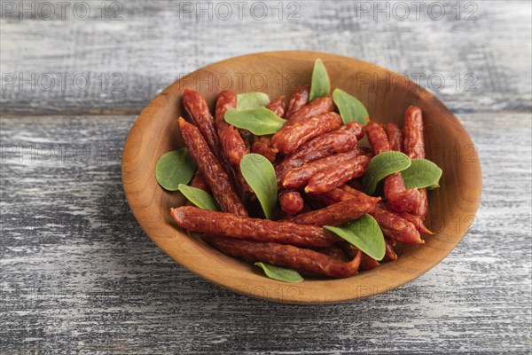 Small smoked sausage with borage microgreen, salt and pepper on gray wooden background. Side view,