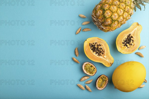 Ripe cut papaya, pineapple, melon, passion fruit, almonds on blue pastel background. Top view, flat