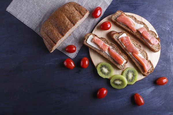 Smoked salmon sandwiches with butter on dark wooden background. cherry tomatoes. top view, copy
