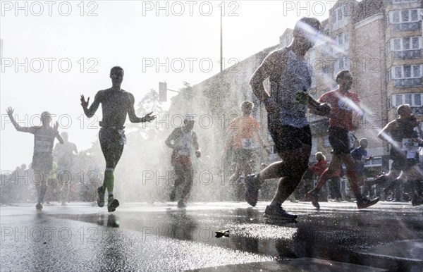 The participants of the Berlin Marathon are cooled down with a water shower in the Schöneberg