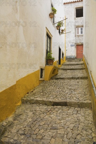Old street with mosaic style paving stone stairs and white roughcast buildings with yellow painted