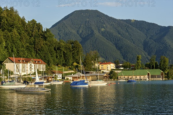 Tegernsee with sailing boats and boat huts, warm evening light, town Tegernsee, mountain Wallberg,