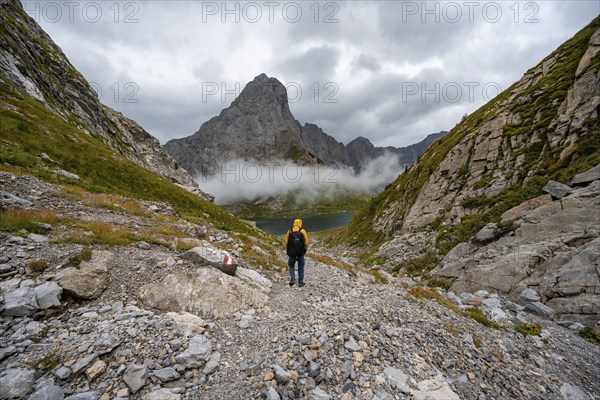 Mountaineers on a hiking trail with a view of rocky cloudy mountains and Wolayersee, hiking trail