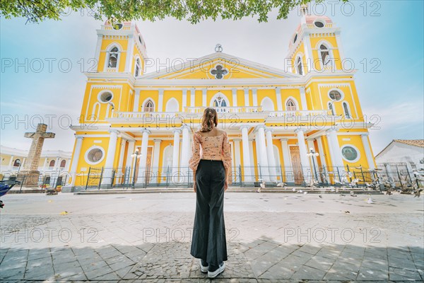 Rear view of a tourist woman in front of a cathedral in a tourist square. Back view of a beautiful
