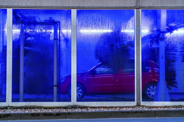 Car in an automatic car wash, car wash tunnel, cleaning foam is sprayed on, rotating brushes clean