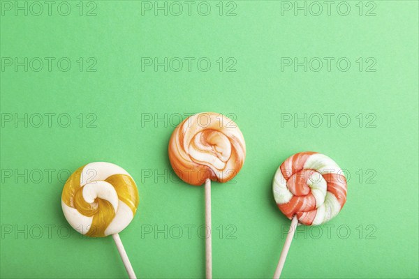 Three lollipop candies on green pastel background. copy space, top view, flat lay