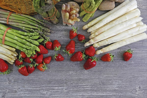 Green asparagus, white asparagus and fresh strawberries decorated on a rustic wooden table