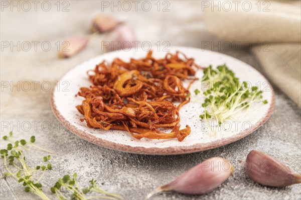 Fried Cordyceps militaris mushrooms on brown concrete background with microgreen, herbs and spices.