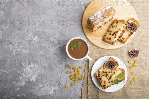 Homemade cake with raisins, dried persimmon and a cup of hot chocolate on a gray concrete
