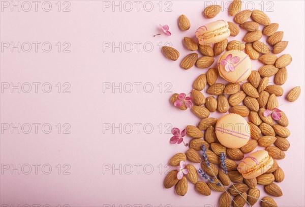 Orange macarons or macaroons cakes with almond nuts on pastel pink background. top view, flat lay,