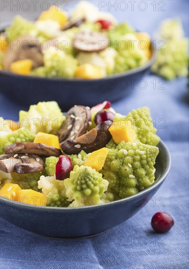 Vegetarian salad from romanesco cabbage, champignons, cranberry, avocado and pumpkin on a black