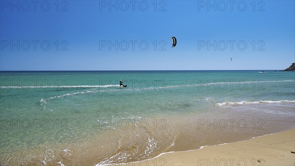 Kitesurfer rides on calm turquoise sea near the beach, surfer's paradise, kitesurfer, windsurfer,