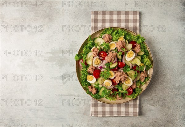 Tuna salad, vegetable salad with quail eggs, lettuce, red onion and cucumbers, on a light gray