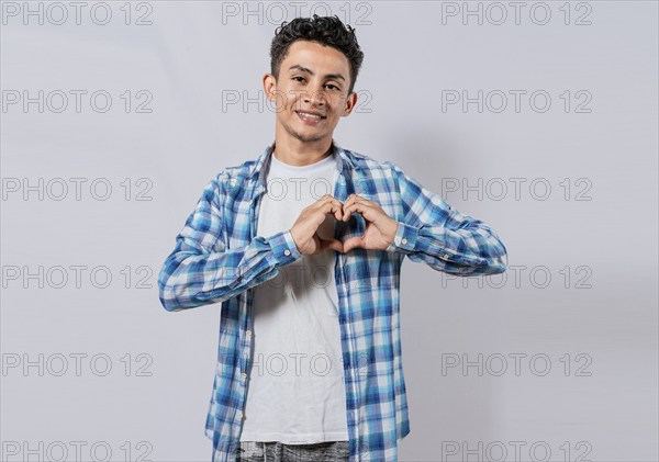 Smiling guy making heart shape with hands isolated. Happy man making heart shape with hands