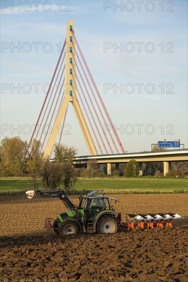 Farmer ploughing a field, tractor with plough, near Neuss, Fleher motorway bridge, A46, North