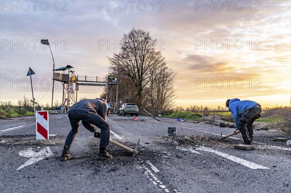 Climate activists chop up the asphalt of a road to erect obstacles, barricades, to prevent the