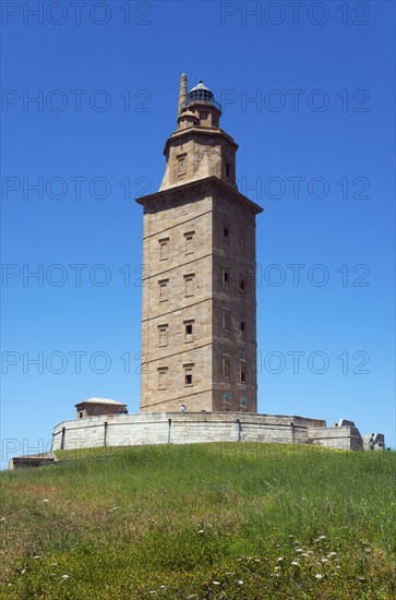 Old lighthouse under a bright blue sky, surrounded by green landscape, Torre de Hércules, Torre de
