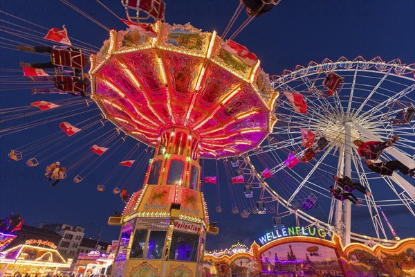 A funfair at dusk with illuminated chain carousel and Ferris wheel, Europa Rad, rides, wave flight,
