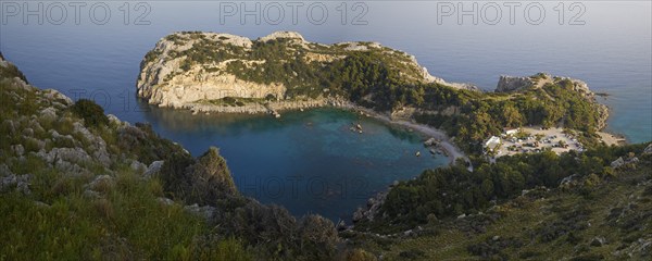 Panoramic view of a rocky bay surrounded by wooded hills and clear, calm waters, Anthony Quinn Bay,