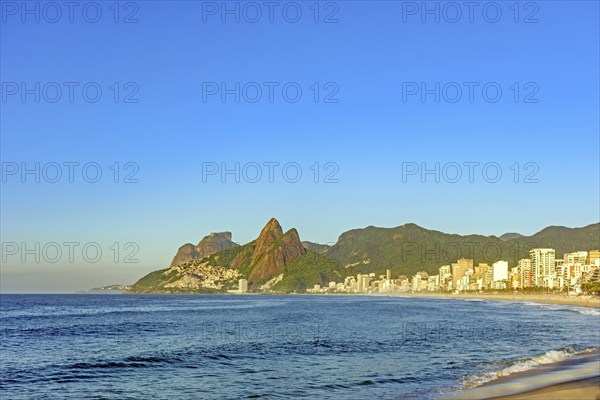 Ipanema Beach in the city of Rio de Janeiro at sunrise with the sea, buildings and mountains, Rio