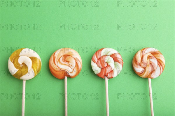Four lollipop candies on green pastel background. copy space, top view, flat lay