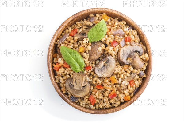 Spelt (dinkel wheat) porridge with vegetables and mushrooms in wooden bowl isolated on white