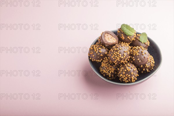 Chocolate caramel ball candies with almonds on a pastel pink background. side view, close up, copy