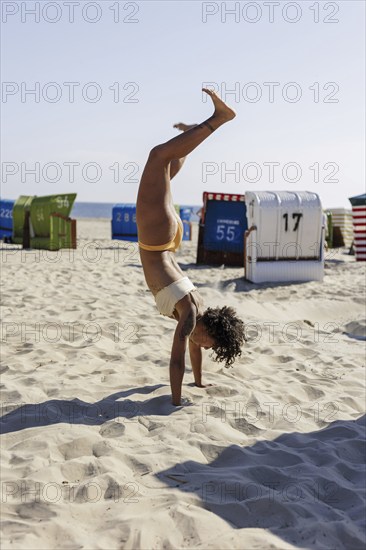 Young woman doing a handstand on the North Sea island of Borkum, 18/05/2024