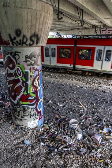 Empty spray paint cans, on a railway line below a road bridge, thrown away, disposed of by the