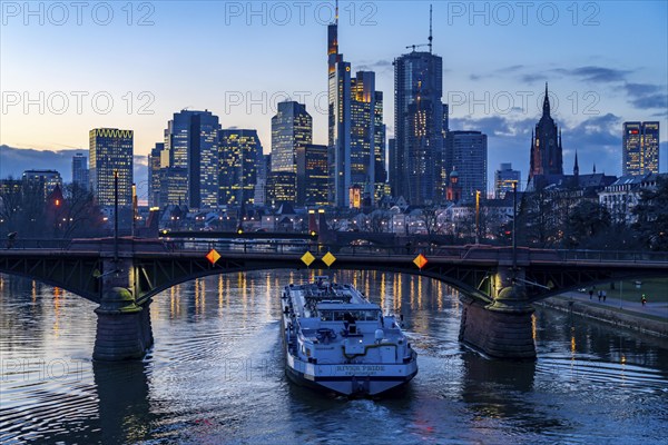 Skyline of the city centre of Frankfurt am Main, river Main, dusk, Ignatz-Bubis-Bridge, cargo ship,