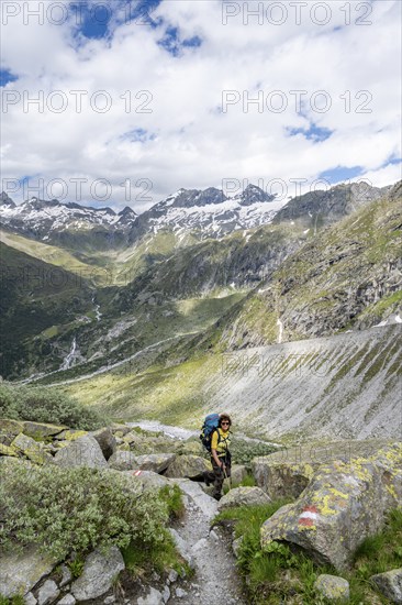 Mountaineer on a hiking trail in front of a picturesque mountain landscape, rocky mountain peaks