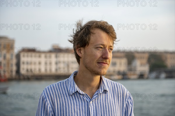 Young man in striped shirt, portrait, on the banks of the Grand Canal, Venice, Veneto, Italy,