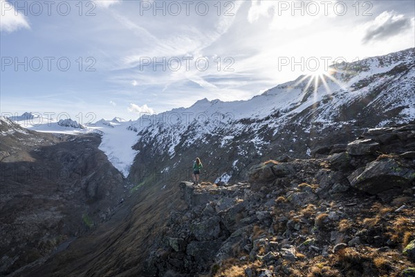 Mountaineer standing on a rock, surrounded by an impressive mountain landscape with snow-covered