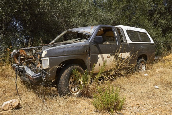 Abandoned rusted car with worn paint in a shady wooded area, wrecked vehicle, Crete, Greek Islands,