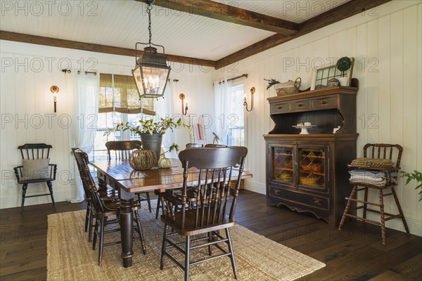 Brown stained pine wood antique reproduction style dining table with high back chairs in dining